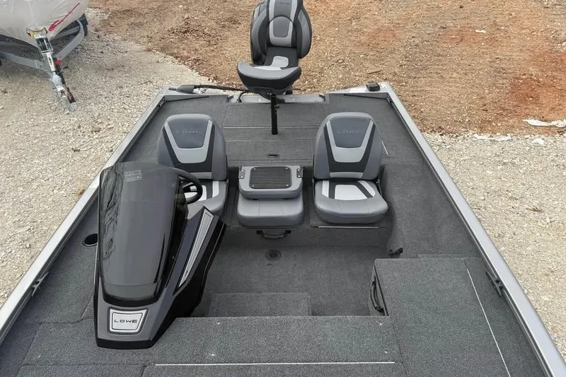 Slide: The Image of 2026 Lowe Stinger 175C boat interior with seating and console, parked on gravel. - 13