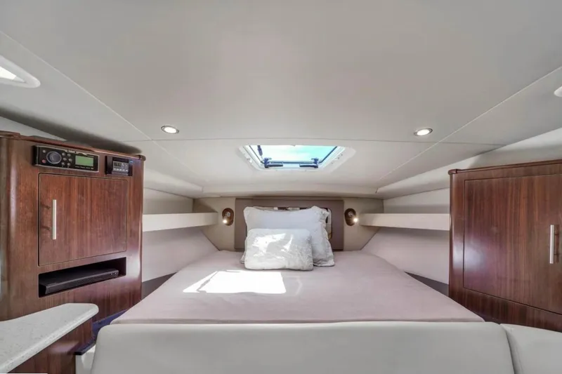 Slide: The Image of 2017 Regal 35 Sport Coupe cabin interior with bed, wood cabinets, and skylight. - 8