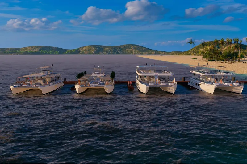 Slide: The Image of Five Custom PAXCAT 2027 catamarans docked at a scenic tropical beach. - 17