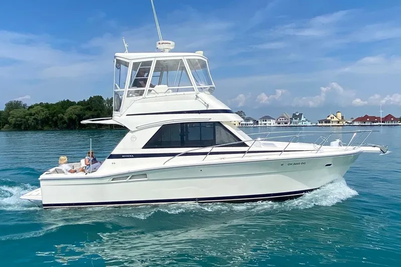 The Image of 2002 Riviera 34 Convertible yacht cruising on clear blue water. - 0