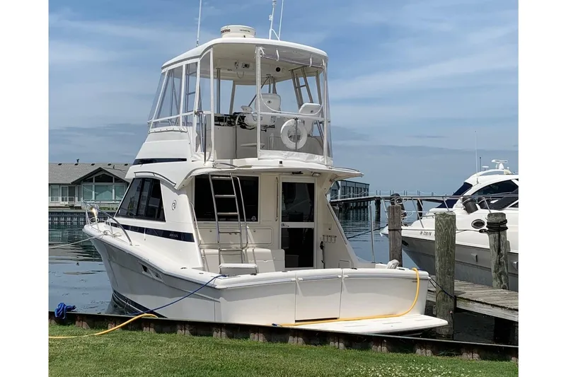 Slide: The Image of 2002 Riviera 34 Convertible yacht helm with Raymarine electronics and steering wheel in a marina. - 3