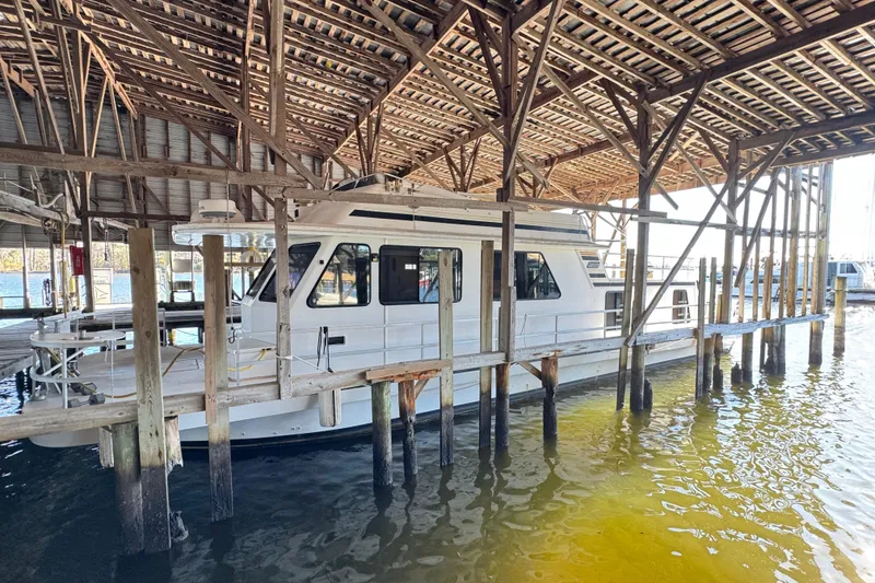 The Image of 1999 Gibson Houseboat 50 docked under wooden shelter in marina. - 0