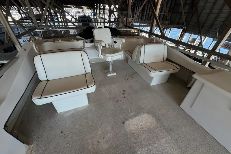 Slide: The Image of 1999 Gibson Houseboat 50 interior with white seating and helm in covered dock. - 10