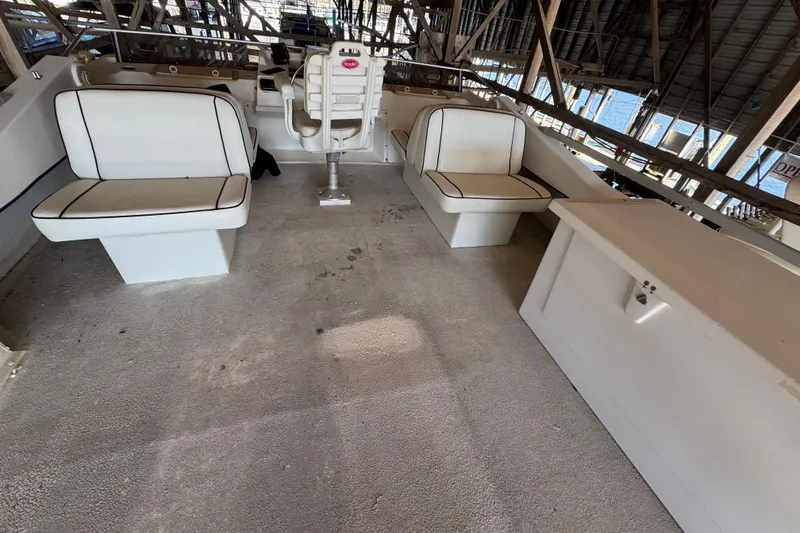 Slide: The Image of 1999 Gibson Houseboat 50 interior with white seating and helm in a covered dock. - 12
