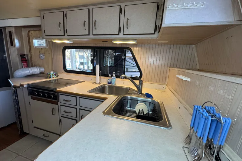 Slide: The Image of 1999 Gibson Houseboat 50 kitchen with sink, stove, cabinets, and utensils. - 40
