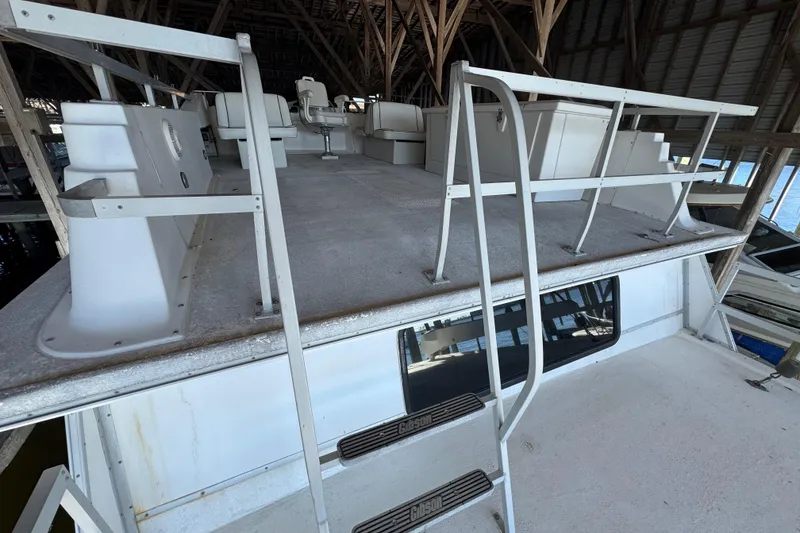 Slide: The Image of 1999 Gibson Houseboat 50 with upper deck seating and railing in covered dock. - 8