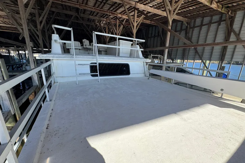 Slide: The Image of 1999 Gibson Houseboat 50 docked in a covered marina, showcasing spacious deck area. - 9