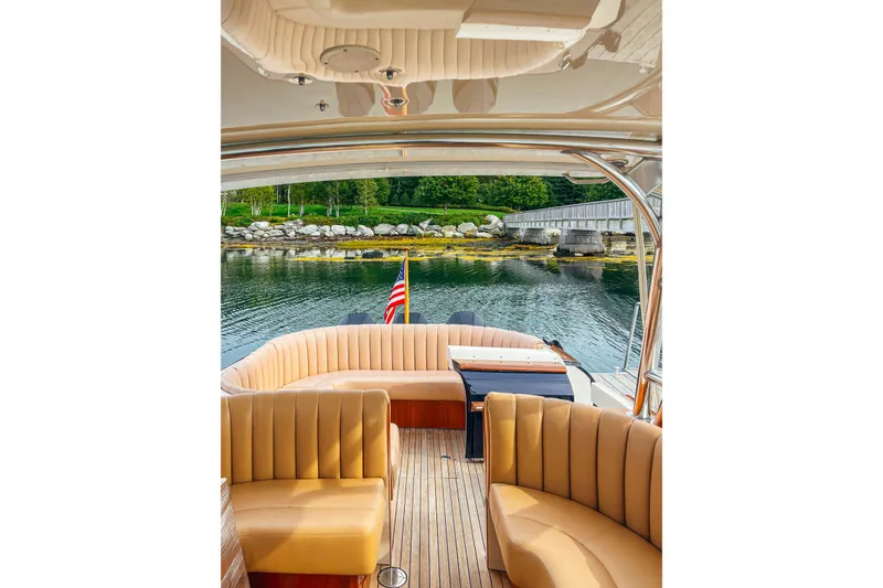 Slide: The Image of 2013 Intrepid 400 Cuddy boat interior with tan seating, docked by a scenic shoreline. - 15