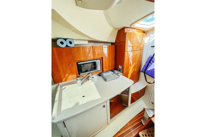 Slide: The Image of 2013 Intrepid 400 Cuddy interior with kitchenette, featuring wood cabinetry and modern amenities. - 22