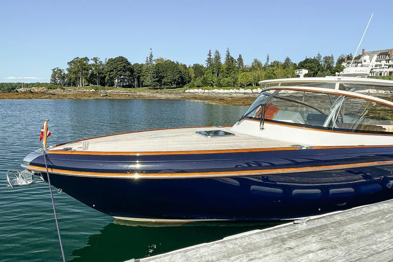 Slide: The Image of 2013 Intrepid 400 Cuddy boat docked on serene water with lush green shoreline. - 3