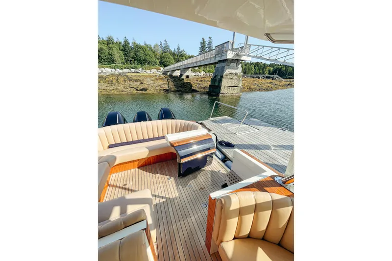 Slide: The Image of 2013 Intrepid 400 Cuddy boat with luxurious seating, docked near a scenic bridge. - 5