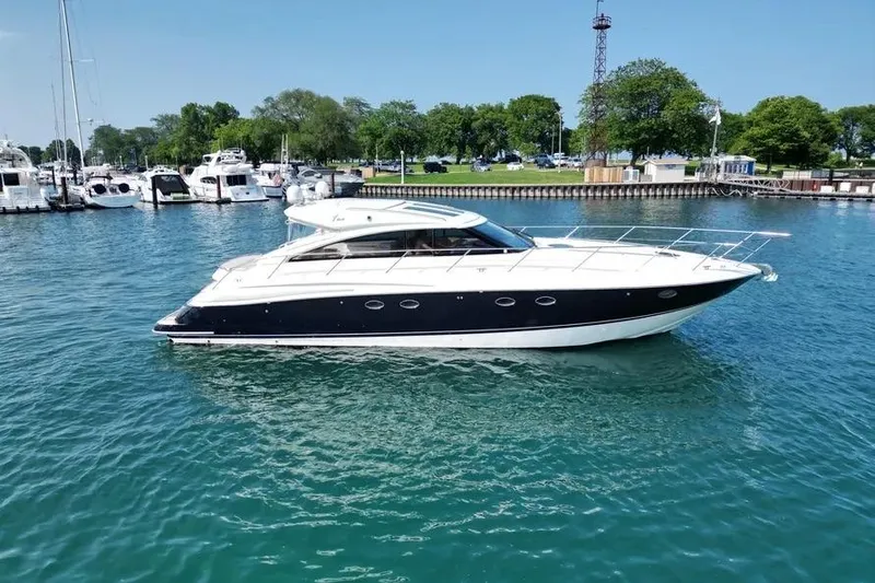 Slide: The Image of 2008 Princess V53 yacht on clear blue water near marina and green shoreline. - 9