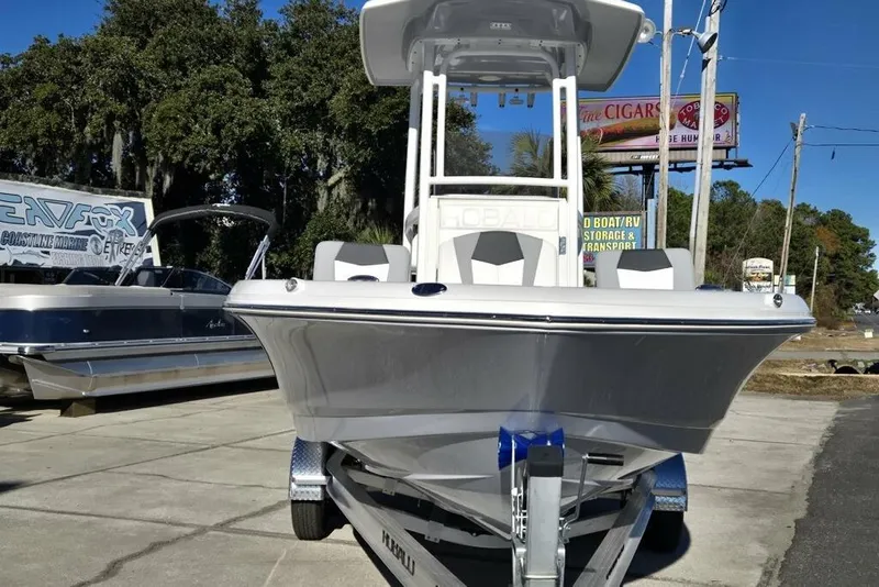 Slide: The Image of 2026 Robalo 246 Cayman boat on trailer, displayed outdoors with trees and signage in background. - 4