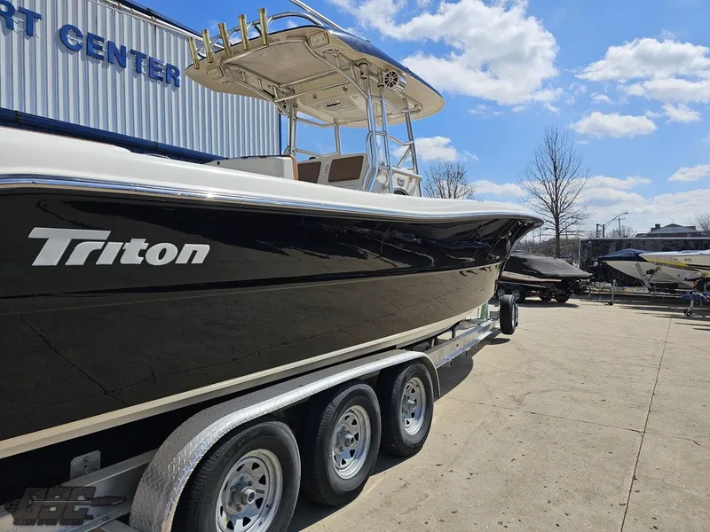 Slide: The Image of 2007 Triton 351 CC boat on a triple-axle trailer at a marine center. - 14