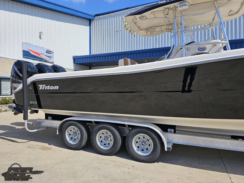 Slide: The Image of 2007 Triton 351 CC boat on a triple-axle trailer outside a building. - 5