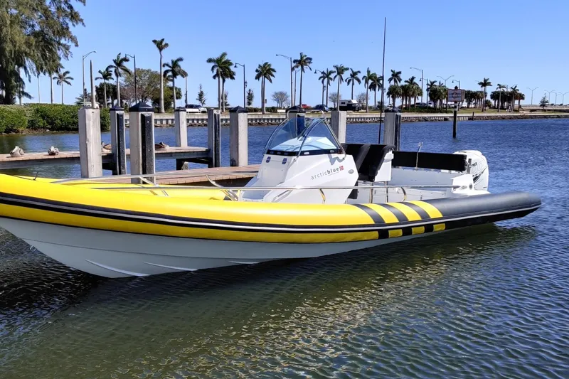 Slide: The Image of 2019 Arctic Blue 29 boat with yellow accents docked by palm trees. - 13