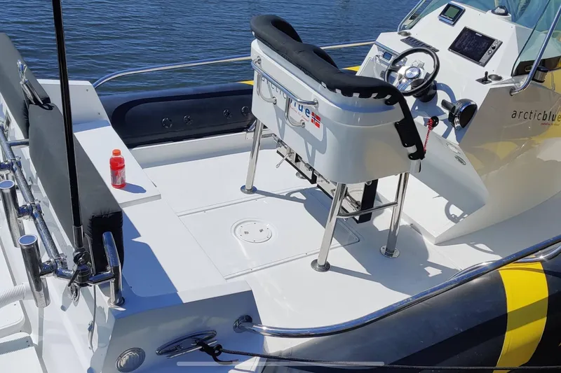 Slide: The Image of 2019 Arctic Blue 29 boat interior with steering console and seating, docked on calm water. - 5