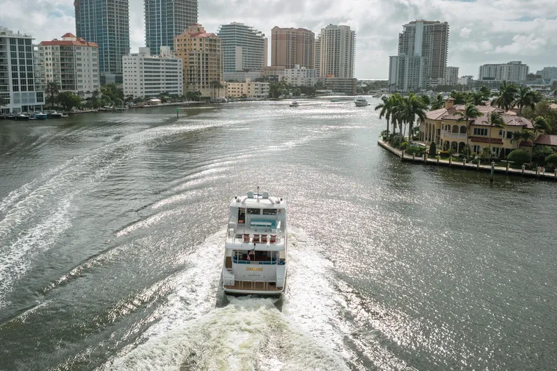 Slide: The Image of Ocean Alexander 80 Motoryacht cruising through a city waterway, surrounded by skyscrapers and palm trees. - 103