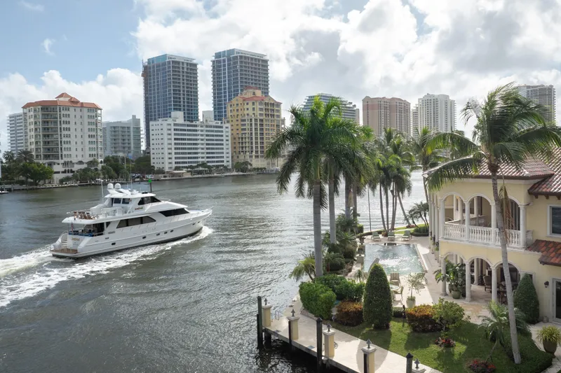 Slide: The Image of 2005 Ocean Alexander 80 Motoryacht cruising near luxury waterfront property with palm trees and city skyline. - 105