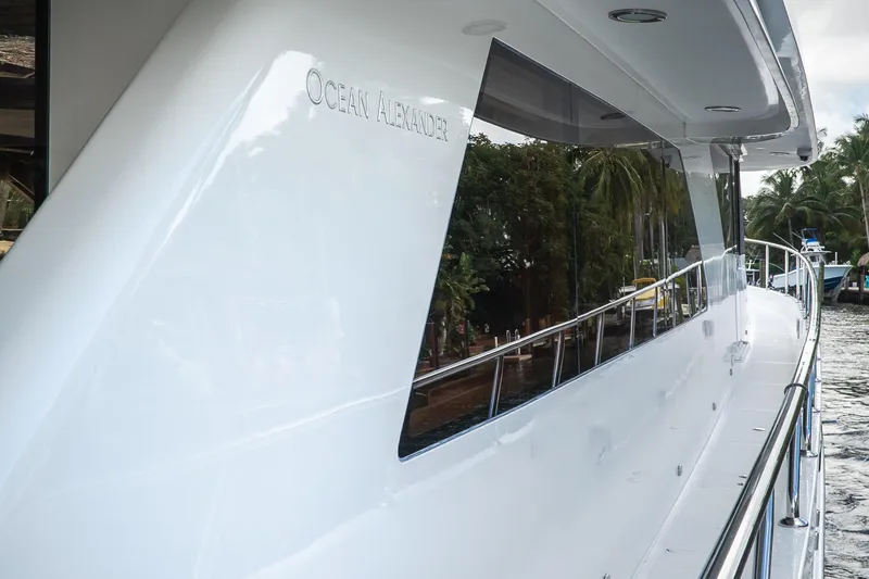 Slide: The Image of 2005 Ocean Alexander 80 Motoryacht, sleek white exterior with railing, docked near palm trees. - 117