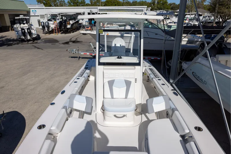 Slide: The Image of 2024 Robalo 246 Cayman boat interior with seating and console, displayed at a marina. - 19