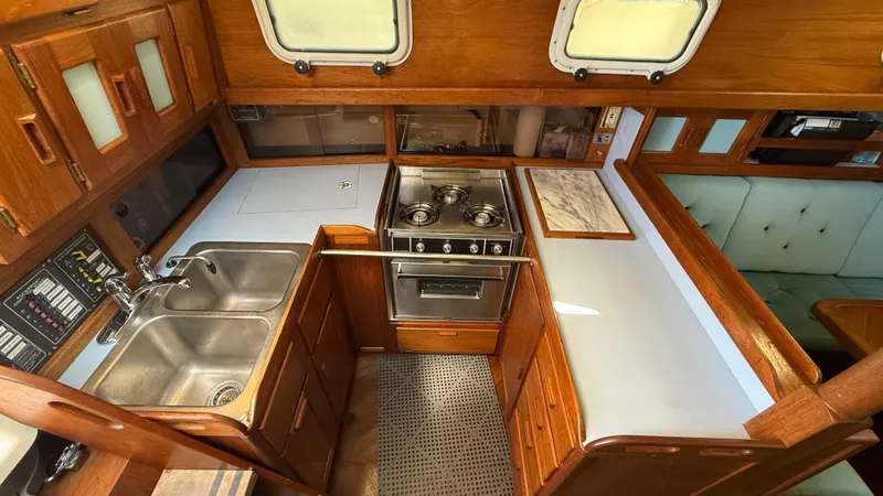 Slide: The Image of Vintage 1984 Cascade 36 yacht kitchen with dual sinks, stove, and wooden cabinetry. - 12