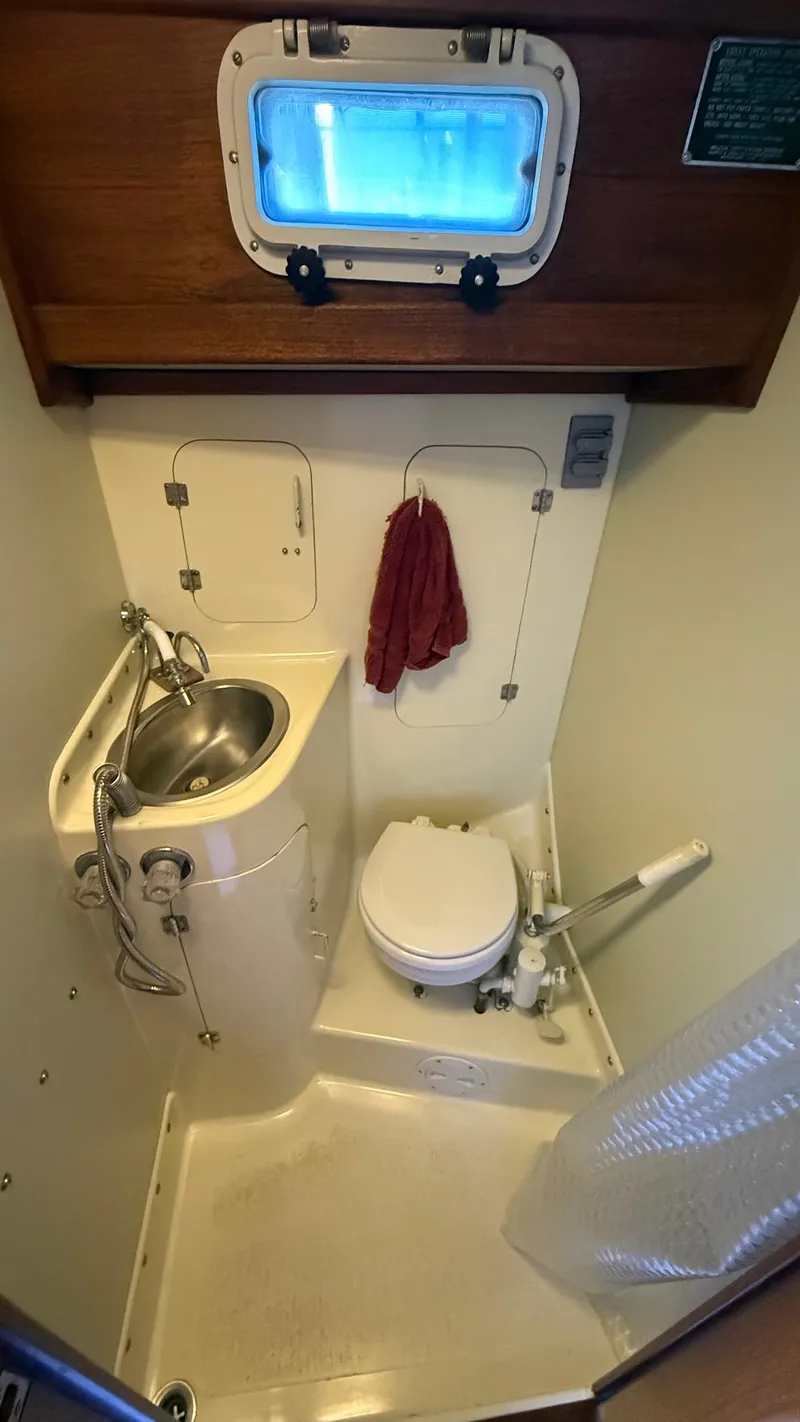 Slide: The Image of Compact 1984 Cascade 36 boat bathroom with sink, toilet, and porthole window. - 19