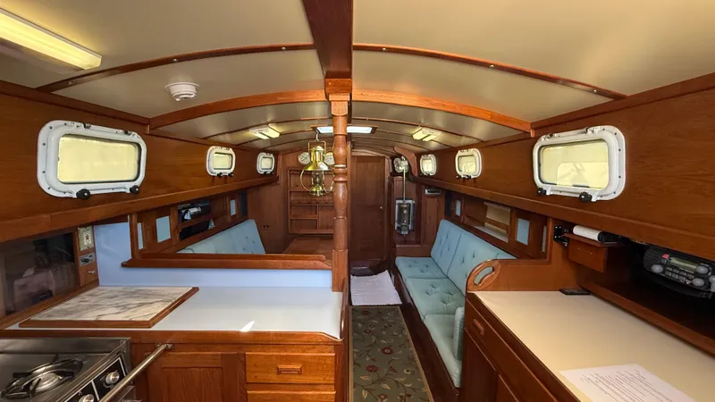 Slide: The Image of 1984 Cascade 36 yacht interior with wood finish, cozy seating, and porthole windows. - 3