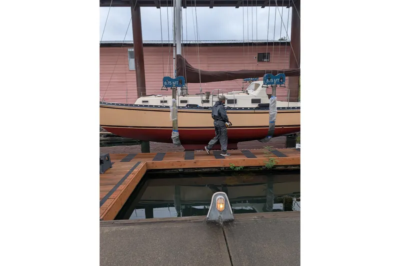 Slide: The Image of Man walking near suspended 1984 Cascade 36 sailboat at dockside. - 31