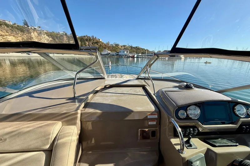 Slide: The Image of 2018 Regal 28 Express boat interior with dashboard, overlooking serene waters and coastal scenery. - 10