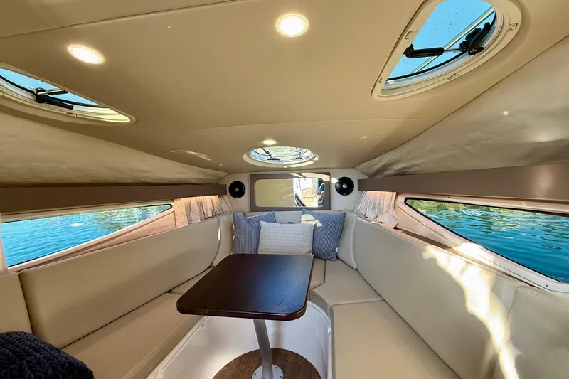 Slide: The Image of 2018 Regal 28 Express cabin interior with seating, table, and windows overlooking water. - 18