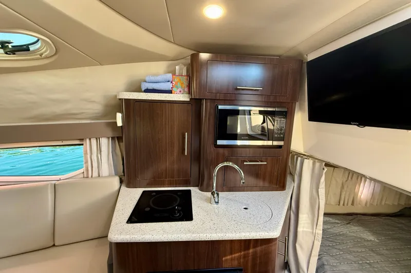 Slide: The Image of Interior of 2018 Regal 28 Express boat featuring kitchenette with microwave and sink. - 20
