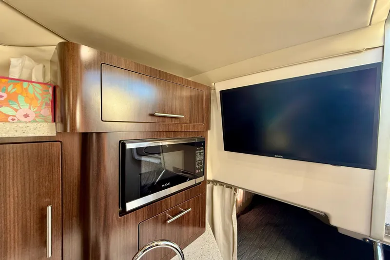 Slide: The Image of 2018 Regal 28 Express interior with microwave, cabinets, and wall-mounted TV. - 23