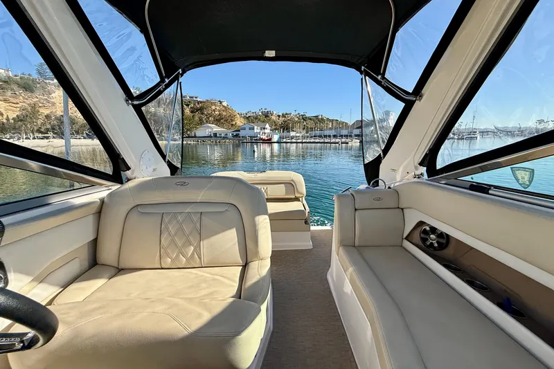 Slide: The Image of 2018 Regal 28 Express boat interior with beige seating, docked in a scenic marina. - 28