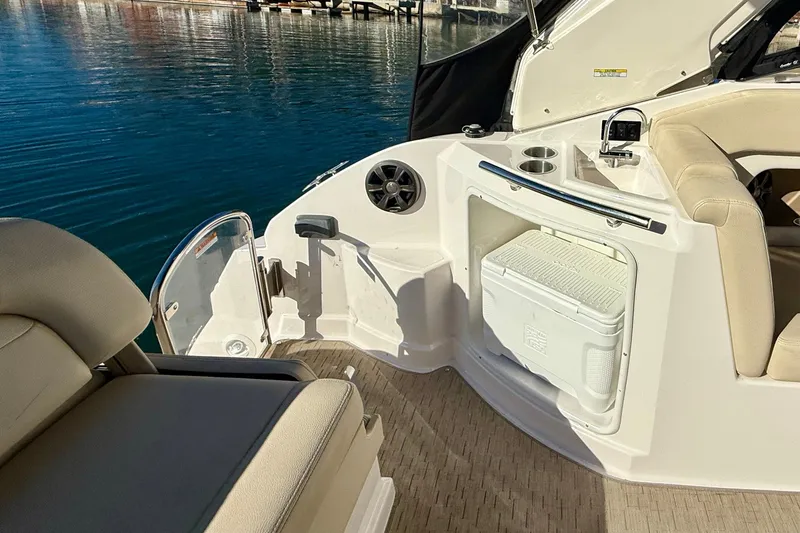 Slide: The Image of 2018 Regal 28 Express boat interior with seating, cooler, and cup holders by the water. - 29