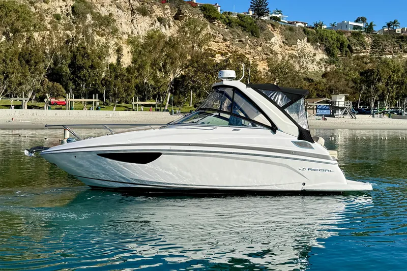 Slide: The Image of 2018 Regal 28 Express boat on calm water near a scenic shoreline. - 3