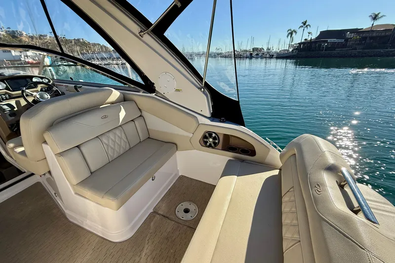 Slide: The Image of 2018 Regal 28 Express boat interior with beige seating, docked in a sunny marina. - 34
