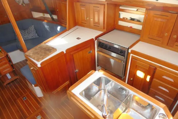 Slide: The Image of Interior of 2002 Tartan 3700 sailboat with wooden cabinetry and kitchen amenities. - 12