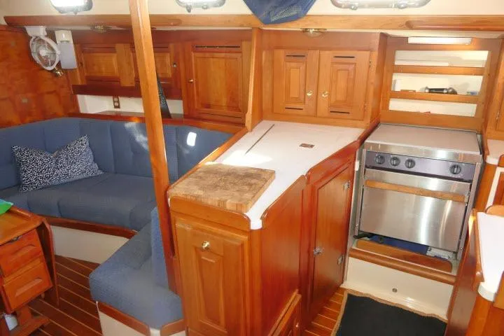 Slide: The Image of Interior of 2002 Tartan 3700 sailboat with wooden cabinetry and cozy seating area. - 13