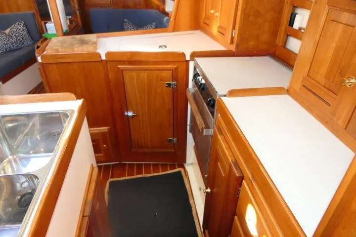 Slide: The Image of Interior of 2002 Tartan 3700 sailboat with wooden cabinetry and compact kitchen area. - 21