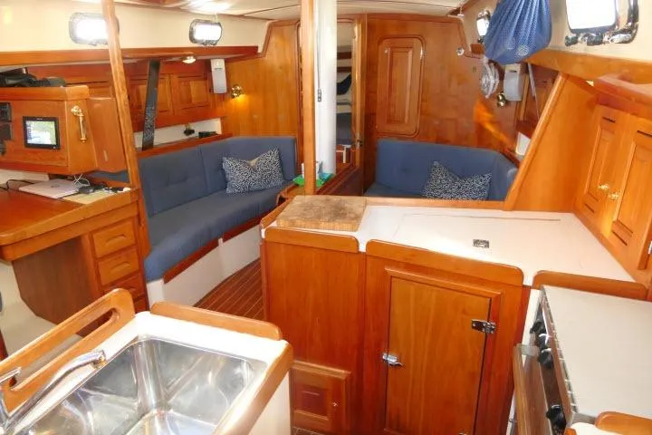 Slide: The Image of Interior of a 2002 Tartan 3700 sailboat with wood finish and blue seating. - 22