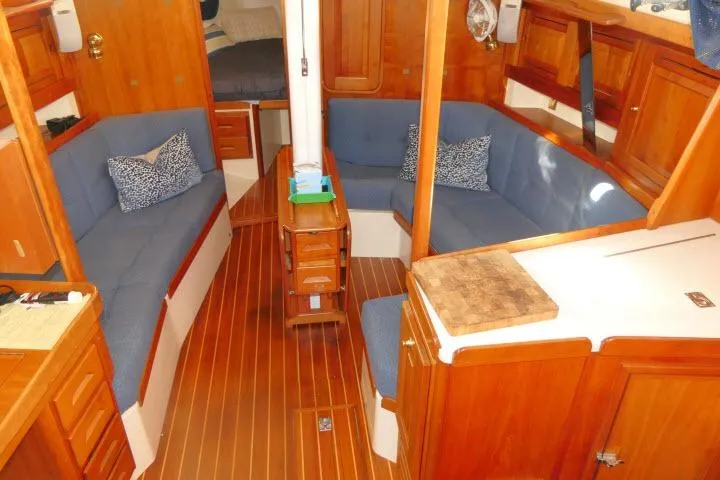 Slide: The Image of Interior of a 2002 Tartan 3700 sailboat with wooden finish and blue seating. - 3