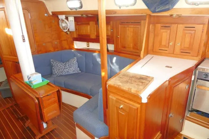 Slide: The Image of Interior of 2002 Tartan 3700 sailboat with wooden cabinetry and blue seating. - 6