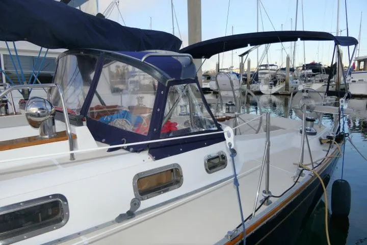 Slide: The Image of 2002 Tartan 3700 sailboat docked in marina, featuring blue canvas covers and sleek design. - 64