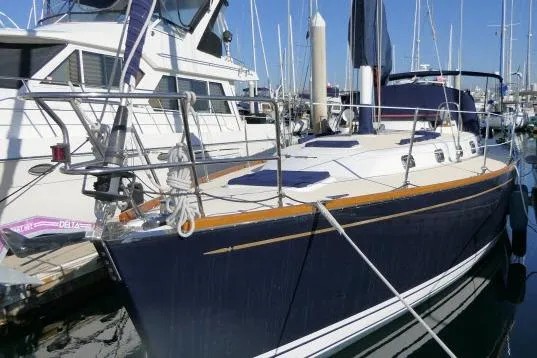 Slide: The Image of 2002 Tartan 3700 sailboat docked at a marina, featuring sleek design and blue hull. - 74