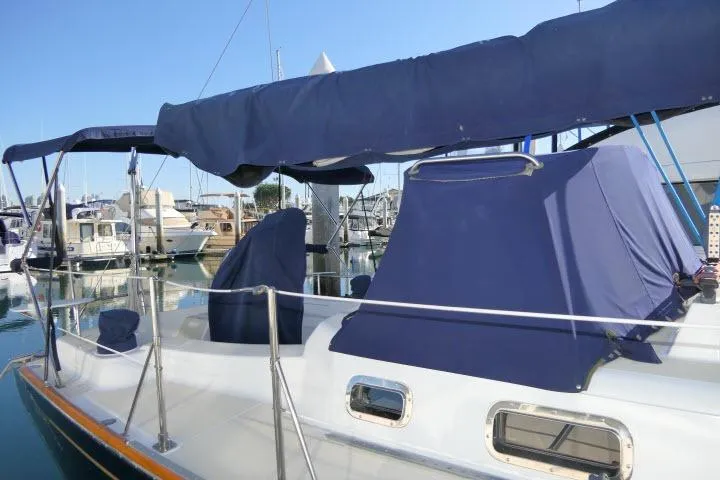 Slide: The Image of 2002 Tartan 3700 sailboat with blue covers docked at a marina. - 80