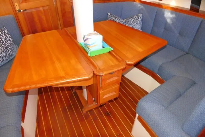 Slide: The Image of Cozy Tartan 3700 sailboat interior with wooden table and blue cushioned seating, 2002 model. - 9