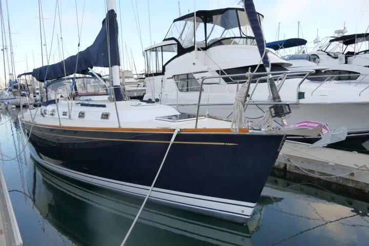 Slide: The Image of 2002 Tartan 3700 sailboat docked in a marina, featuring a sleek navy hull. - 94