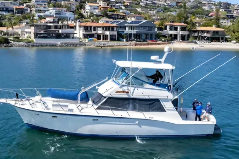 The Image of 1987 Hatteras 52 Convertible yacht cruising near coastal homes. - 0