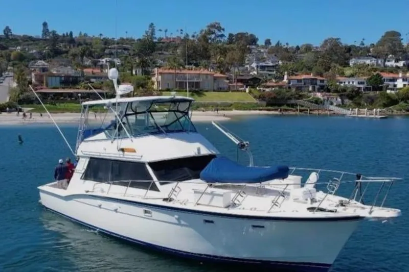 Slide: The Image of 1987 Hatteras 52 Convertible yacht on calm water near a scenic coastal town. - 1